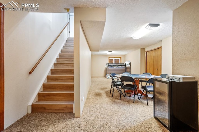 stairway featuring a textured ceiling and carpet floors