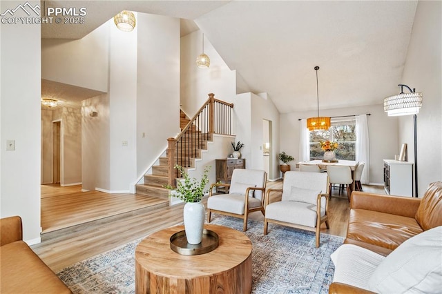 living room featuring hardwood / wood-style floors, high vaulted ceiling, and a notable chandelier