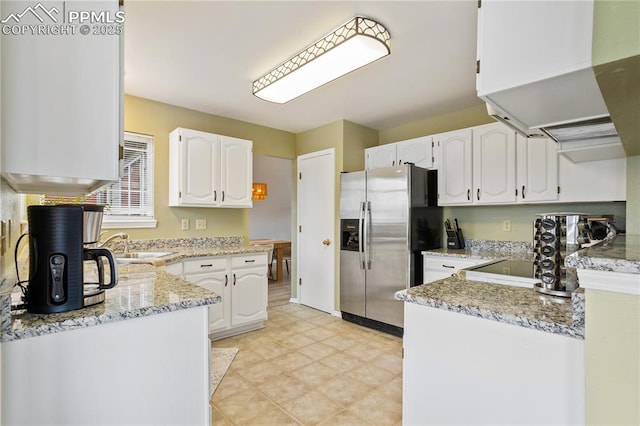 kitchen featuring light stone countertops, extractor fan, sink, white cabinets, and stainless steel fridge with ice dispenser