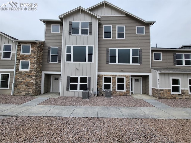 view of front of home with central air condition unit, stone siding, and board and batten siding