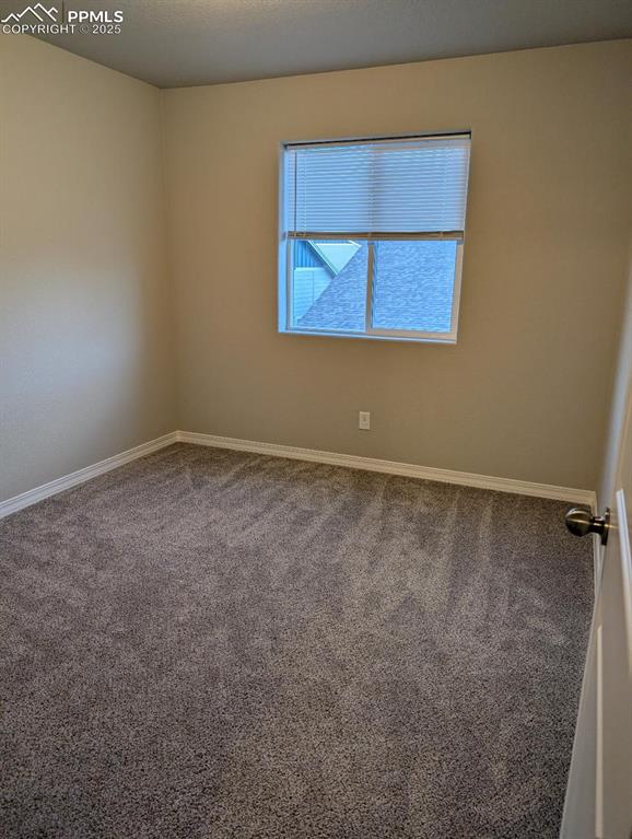 empty room with carpet, a textured ceiling, and baseboards