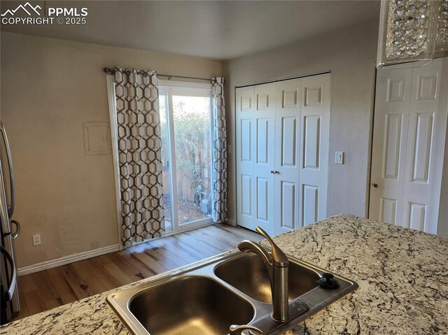 kitchen featuring light stone counters, sink, and wood-type flooring