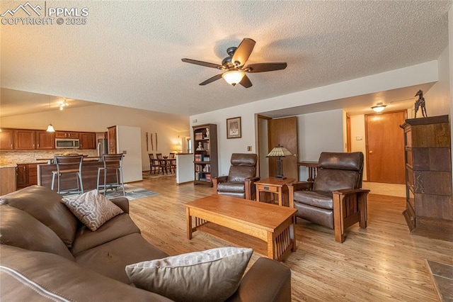 living room with a textured ceiling, light hardwood / wood-style flooring, and ceiling fan