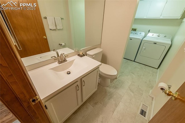 bathroom featuring washing machine and clothes dryer, a skylight, vanity, and toilet