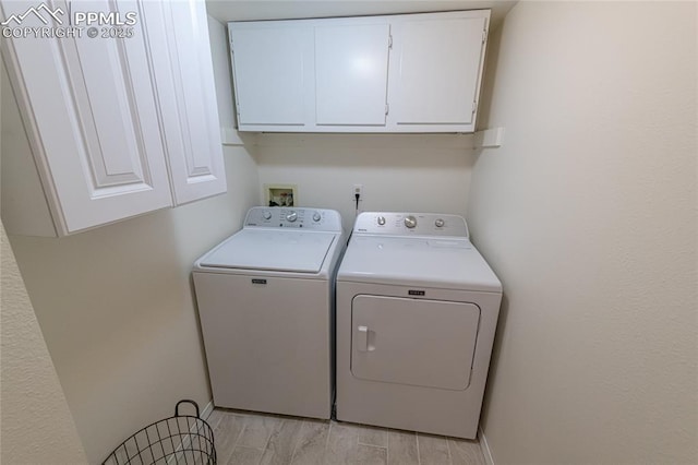 clothes washing area featuring washer and clothes dryer and cabinets