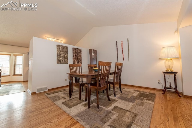 dining area featuring hardwood / wood-style flooring and vaulted ceiling