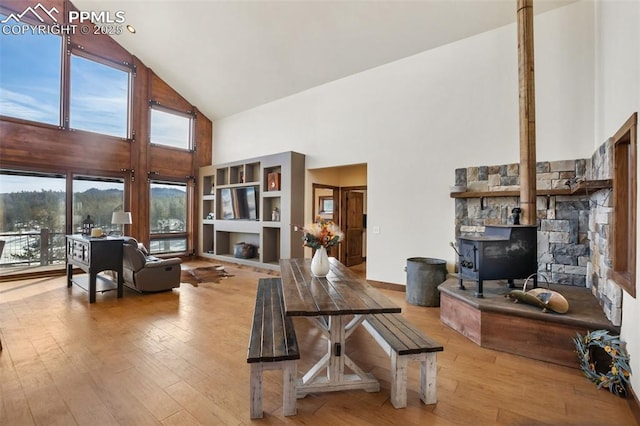 living area with a wood stove, high vaulted ceiling, and wood finished floors