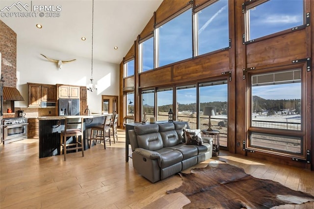 living area featuring light wood-style flooring, a chandelier, vaulted ceiling, and recessed lighting