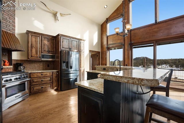 kitchen featuring light wood finished floors, plenty of natural light, a breakfast bar area, and stainless steel appliances