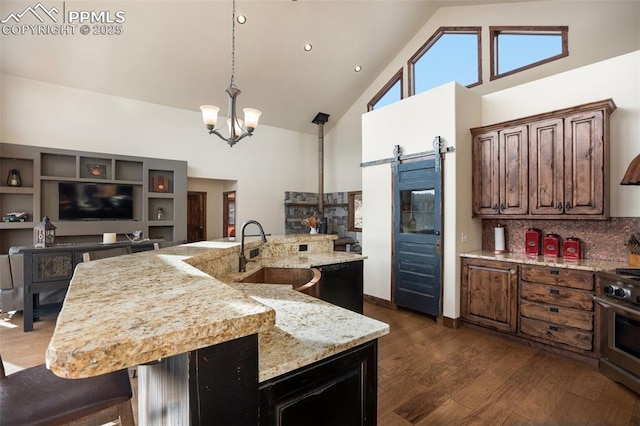 kitchen featuring dark wood-style flooring, stainless steel stove, a barn door, a sink, and high vaulted ceiling