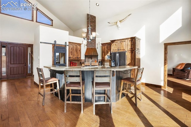 kitchen featuring stainless steel appliances, a barn door, high vaulted ceiling, and hardwood / wood-style floors