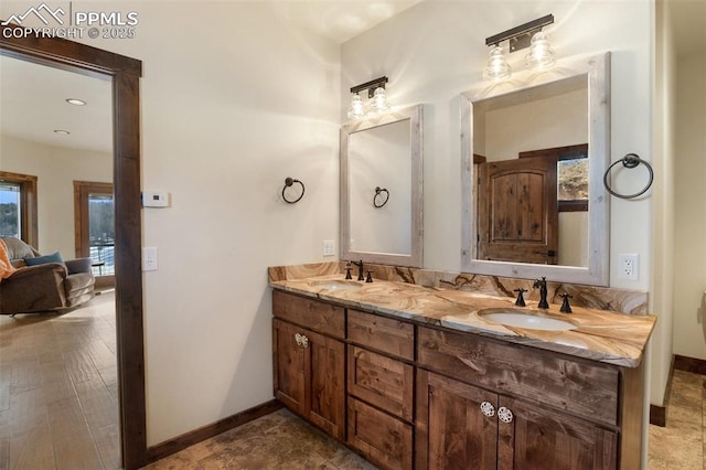 full bath featuring a sink, baseboards, and double vanity