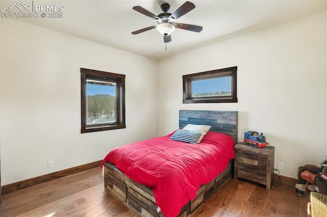 bedroom with a ceiling fan, baseboards, and wood finished floors