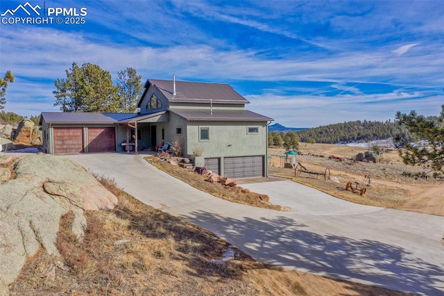 view of front of home featuring a garage, driveway, and metal roof