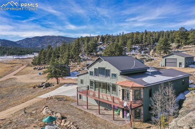 rear view of house with metal roof, a detached garage, and a deck with mountain view