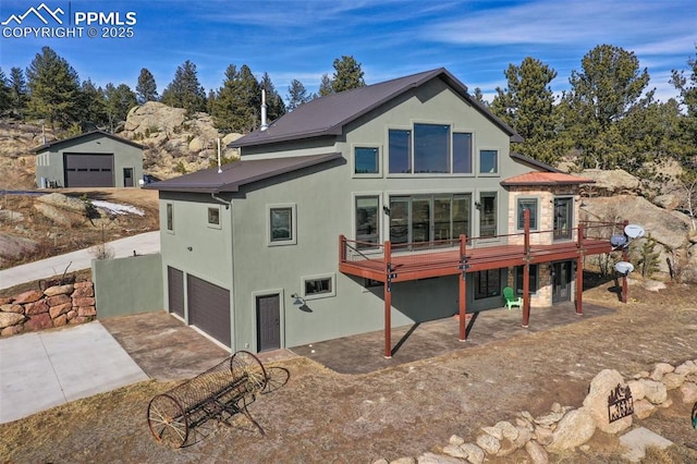 back of house with a deck, concrete driveway, a garage, and stucco siding