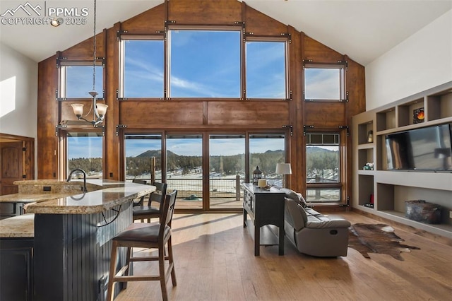 interior space featuring built in shelves, high vaulted ceiling, a chandelier, and wood finished floors