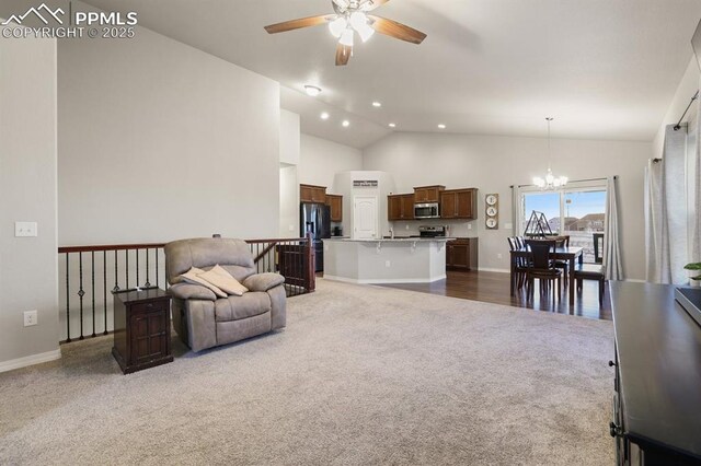 carpeted living room with ceiling fan with notable chandelier and high vaulted ceiling