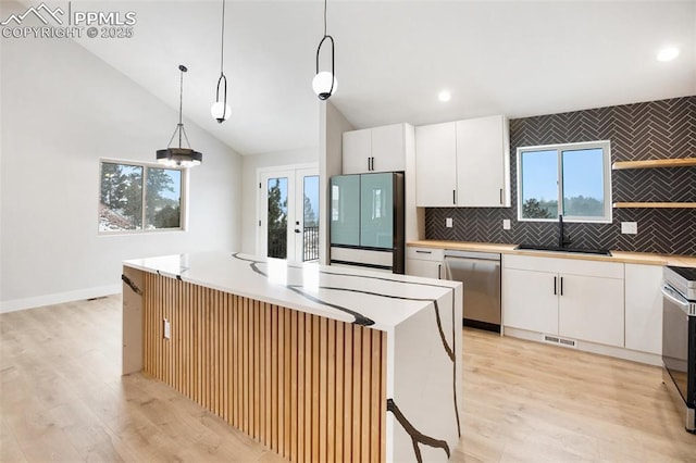 kitchen with white cabinetry, sink, a center island, hanging light fixtures, and appliances with stainless steel finishes