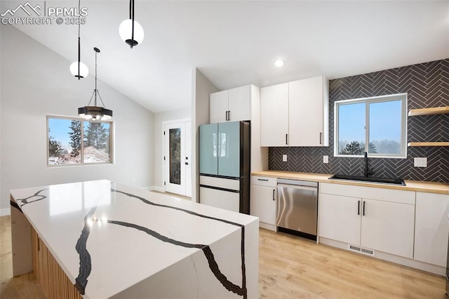 kitchen with white cabinets, decorative light fixtures, sink, and appliances with stainless steel finishes