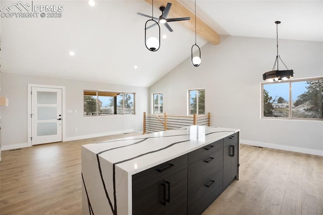 kitchen with ceiling fan with notable chandelier, a spacious island, hanging light fixtures, beamed ceiling, and light hardwood / wood-style floors