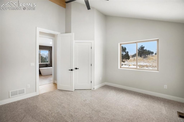 unfurnished bedroom with multiple windows, ceiling fan, carpet, and vaulted ceiling