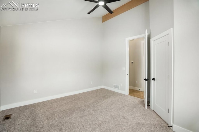 carpeted spare room featuring ceiling fan and lofted ceiling