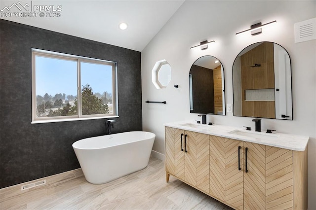 bathroom featuring a bathtub, vanity, and lofted ceiling