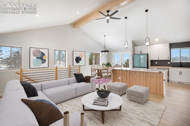 living room with beamed ceiling, plenty of natural light, and ceiling fan