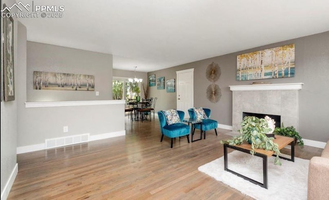 living room with hardwood / wood-style flooring, a fireplace, and a chandelier