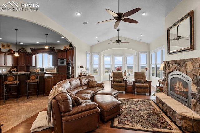 living room with tile patterned floors, ceiling fan, a fireplace, and vaulted ceiling