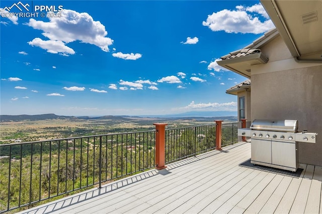 wooden deck with a mountain view and area for grilling