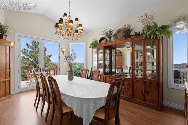 dining room with hardwood / wood-style flooring, french doors, a healthy amount of sunlight, and an inviting chandelier