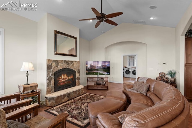 living room featuring lofted ceiling, hardwood / wood-style flooring, ceiling fan, separate washer and dryer, and a fireplace