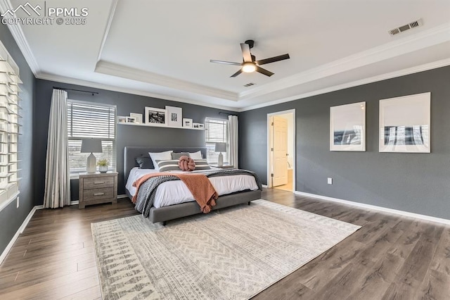 bedroom with hardwood / wood-style flooring, ceiling fan, crown molding, and a tray ceiling