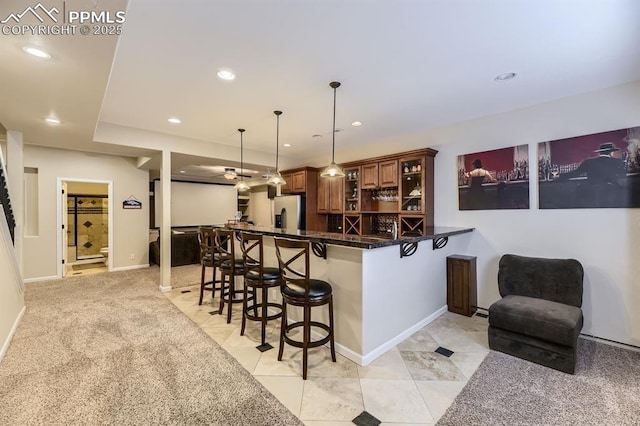 kitchen with a breakfast bar, dark stone counters, stainless steel refrigerator with ice dispenser, hanging light fixtures, and kitchen peninsula