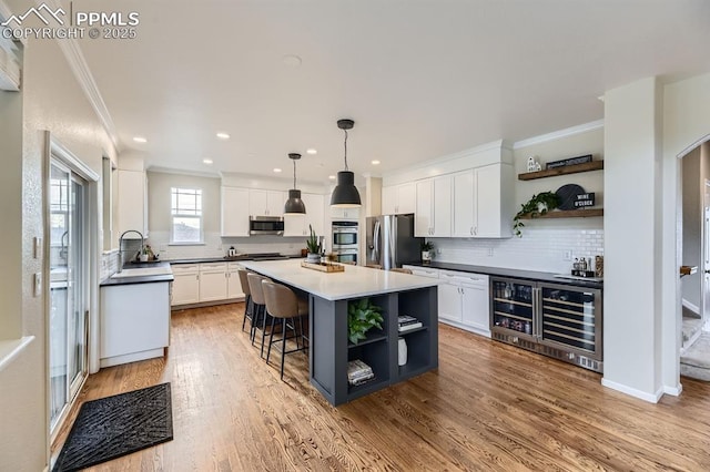 kitchen featuring a center island, white cabinets, hanging light fixtures, light hardwood / wood-style flooring, and stainless steel appliances