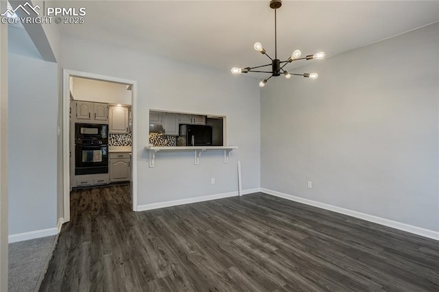 kitchen featuring a kitchen breakfast bar, backsplash, kitchen peninsula, gray cabinets, and black appliances