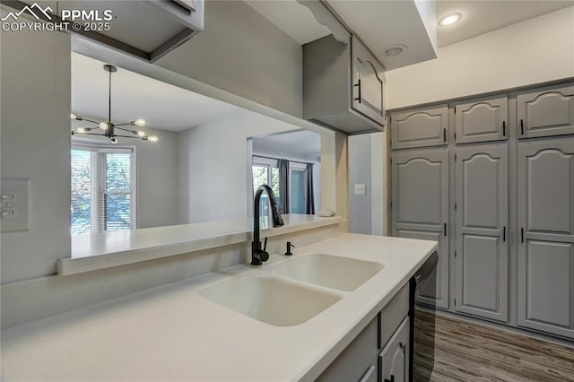 kitchen with dishwasher, sink, an inviting chandelier, dark hardwood / wood-style flooring, and gray cabinets