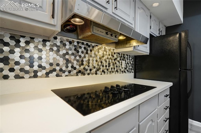 kitchen with black electric stovetop, decorative backsplash, and white cabinets