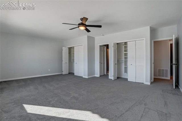 unfurnished bedroom with ceiling fan, dark carpet, and two closets