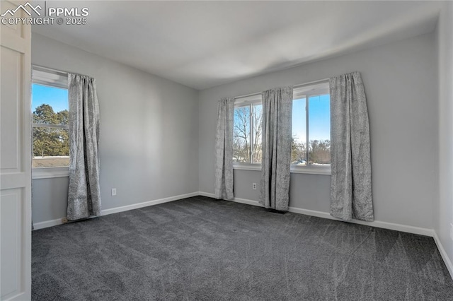 empty room with dark carpet and a wealth of natural light