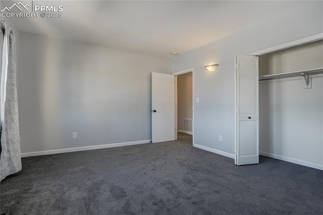 unfurnished bedroom with dark carpet and a closet