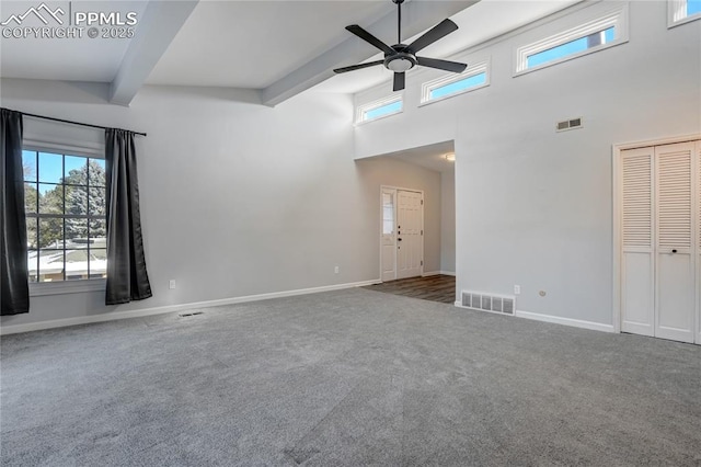 carpeted spare room with ceiling fan, beamed ceiling, and a high ceiling