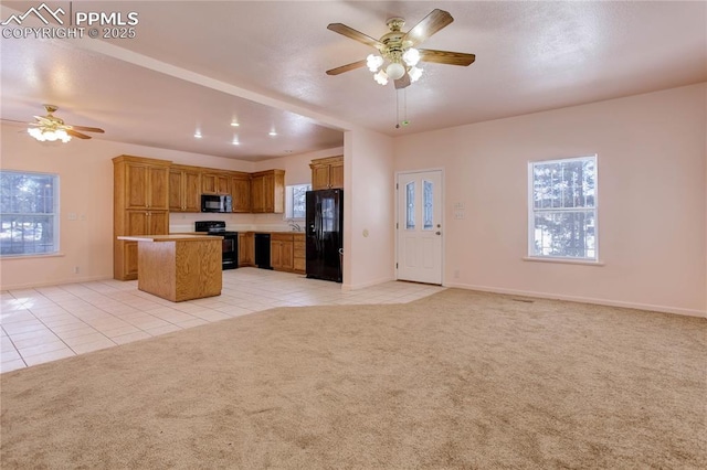 kitchen featuring black appliances, light colored carpet, a kitchen island, and ceiling fan