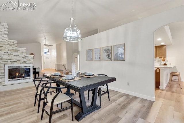 dining space featuring ceiling fan, a fireplace, and light wood-type flooring