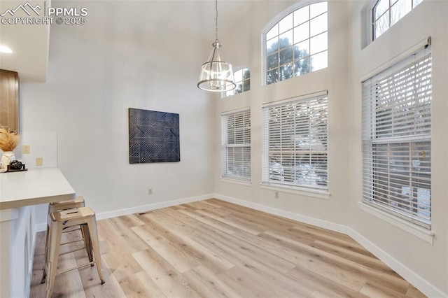 unfurnished dining area with light wood-type flooring and a notable chandelier