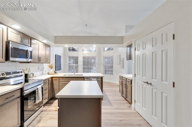 kitchen featuring a center island, sink, light hardwood / wood-style floors, kitchen peninsula, and stainless steel appliances