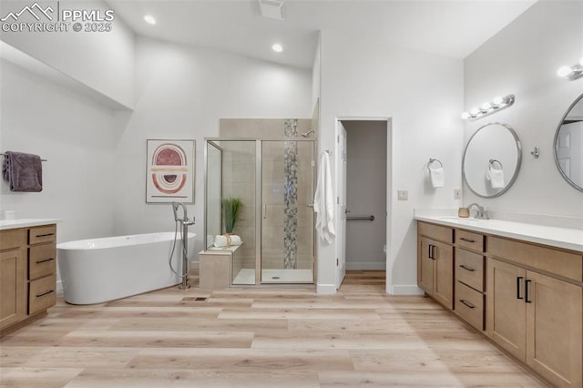 bathroom with separate shower and tub, a towering ceiling, hardwood / wood-style floors, and vanity