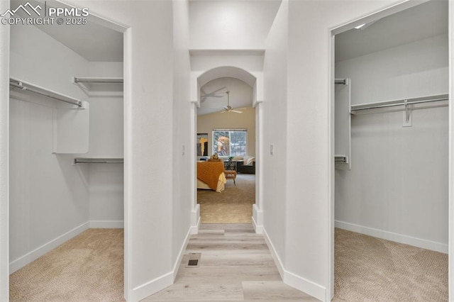 walk in closet with light colored carpet, ceiling fan, and lofted ceiling